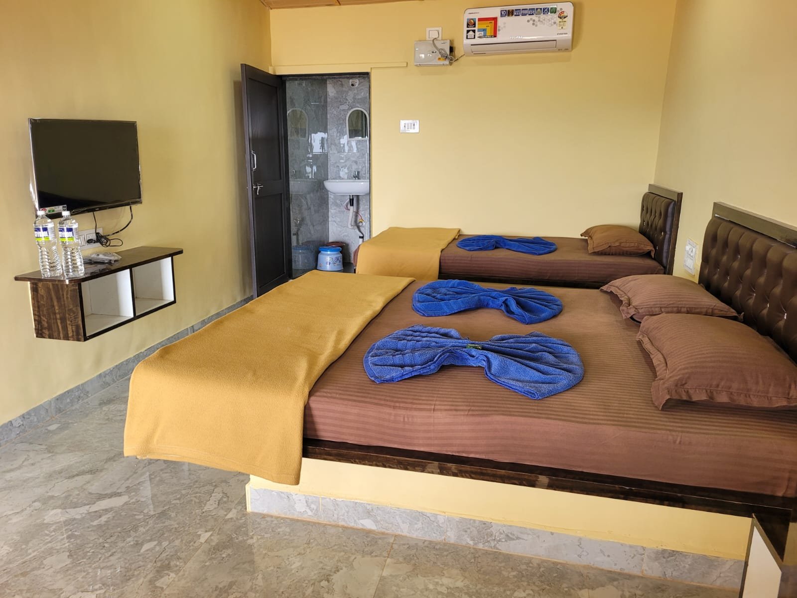 Guest room with multiple beds, television, and air conditioning